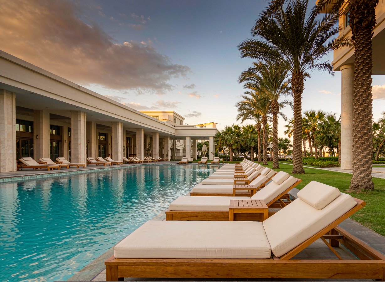 Row of teak sun loungers along a resort swimming pool at golden hour