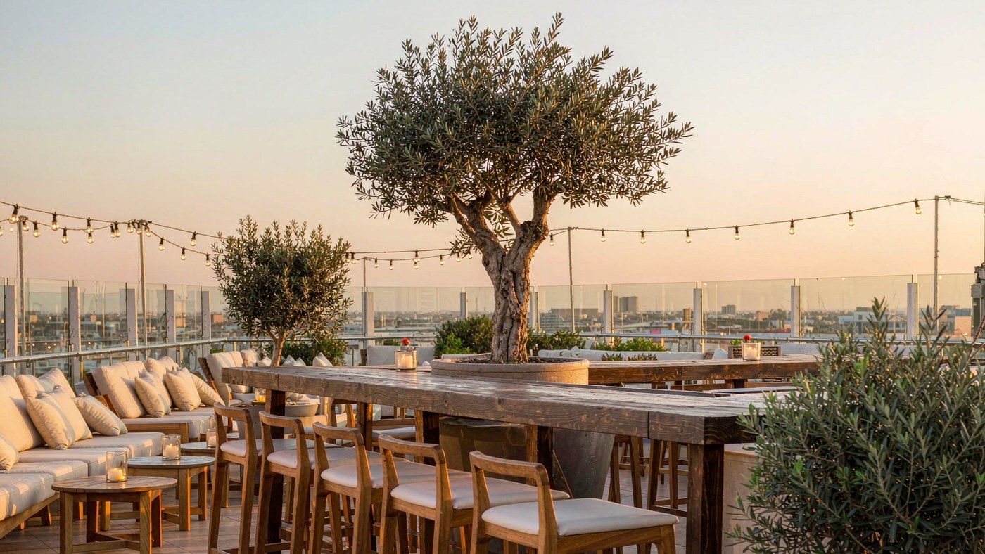 Rooftop bar terrace furnished with teak and rope outdoor seating above a city skyline at dusk