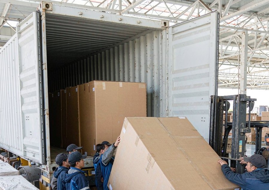 Workers loading large furniture cartons into a container at the PatioHue loading dock