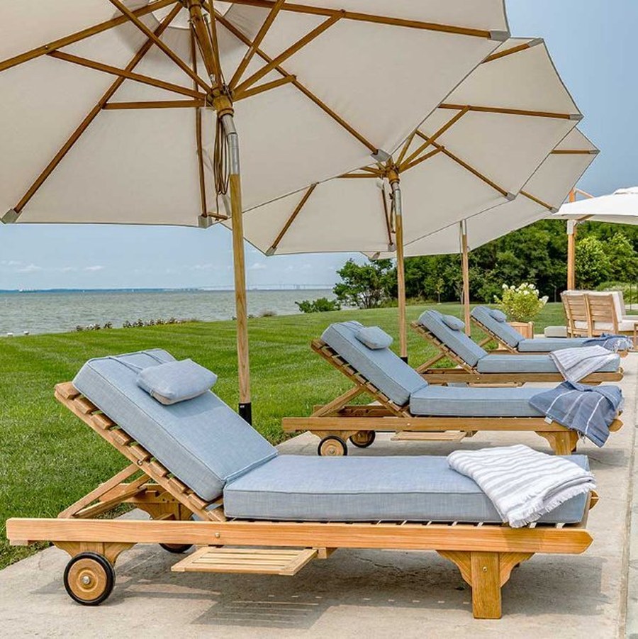 Teak sun loungers with parasols on a lawn overlooking the sea
