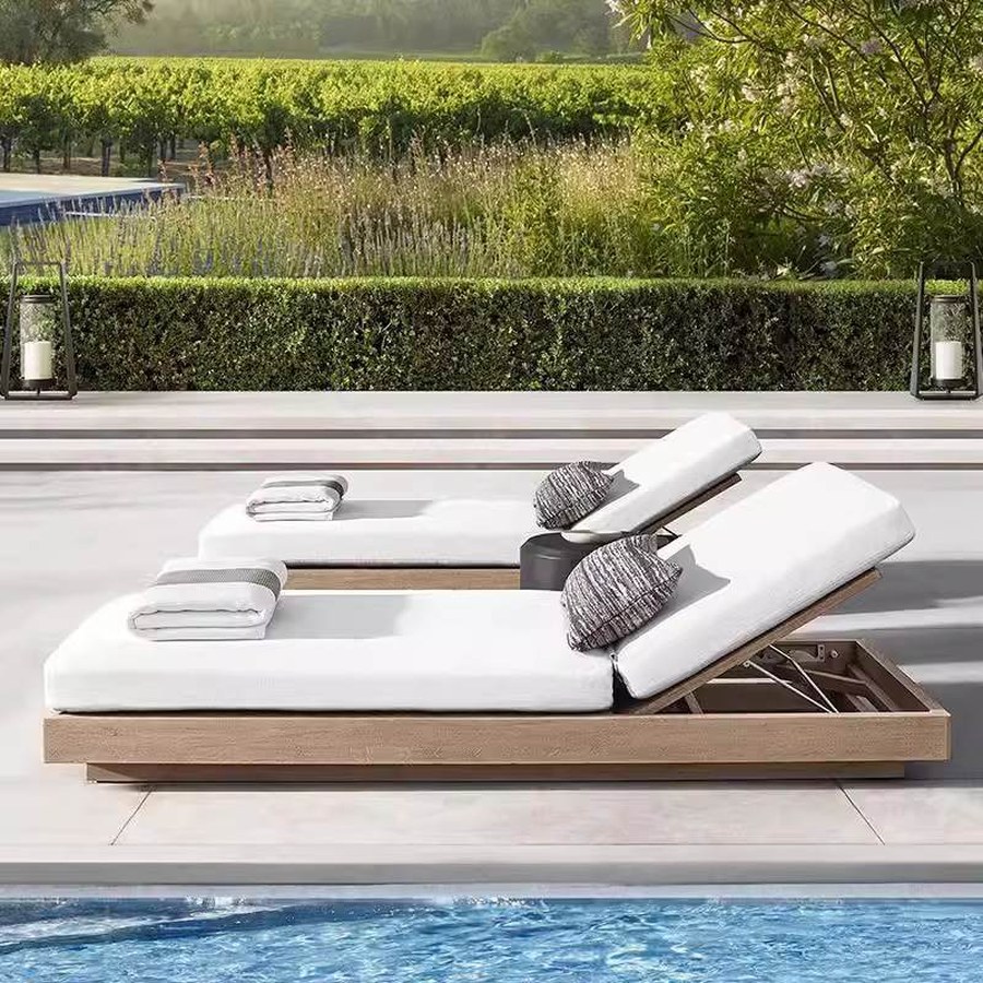 Teak sun loungers with white cushions beside a swimming pool