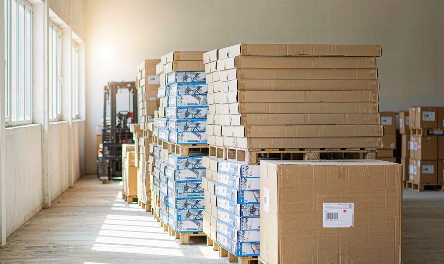 Flat-packed outdoor furniture cartons on pallets in a warehouse aisle ready for container loading