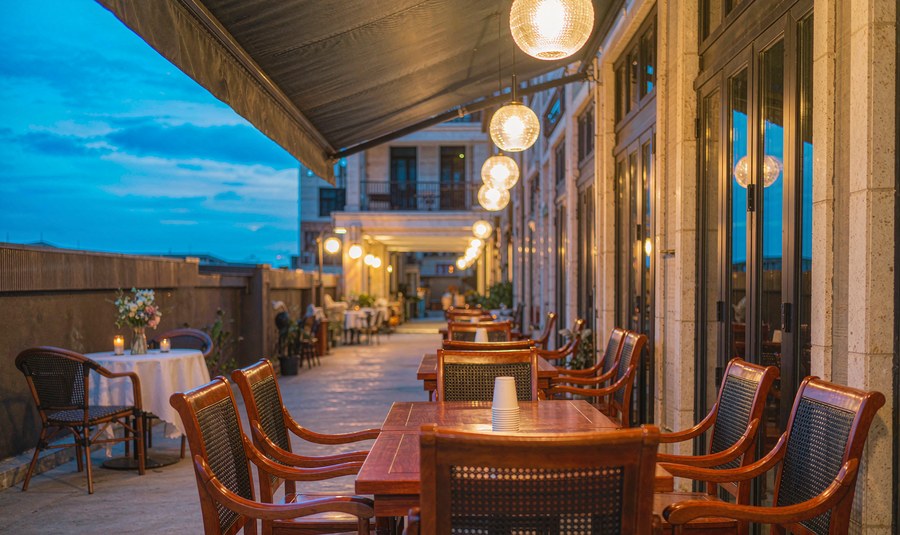 Restaurant terrace at dusk with teak dining sets, pendant lights and candles